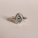 Silver ring with a gemstone on a beige background