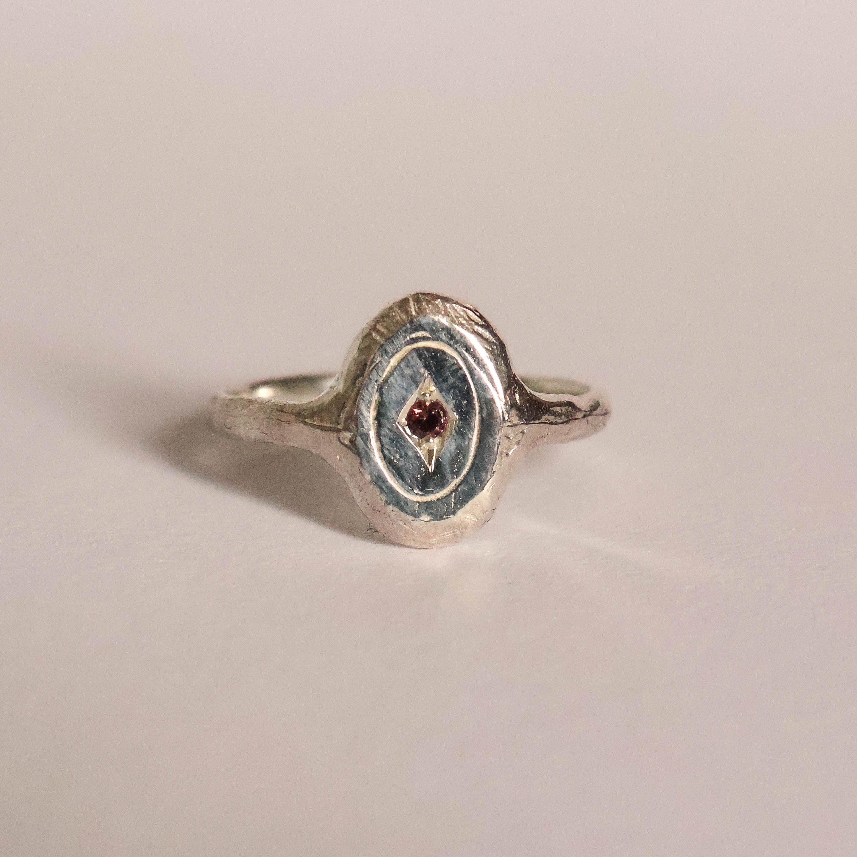 Silver ring with a gemstone on a beige background