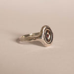 Silver ring with a red gemstone on a beige background