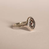 Silver ring with a red gemstone on a beige background