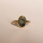 Gold ring with a star set blue sapphire on a beige background