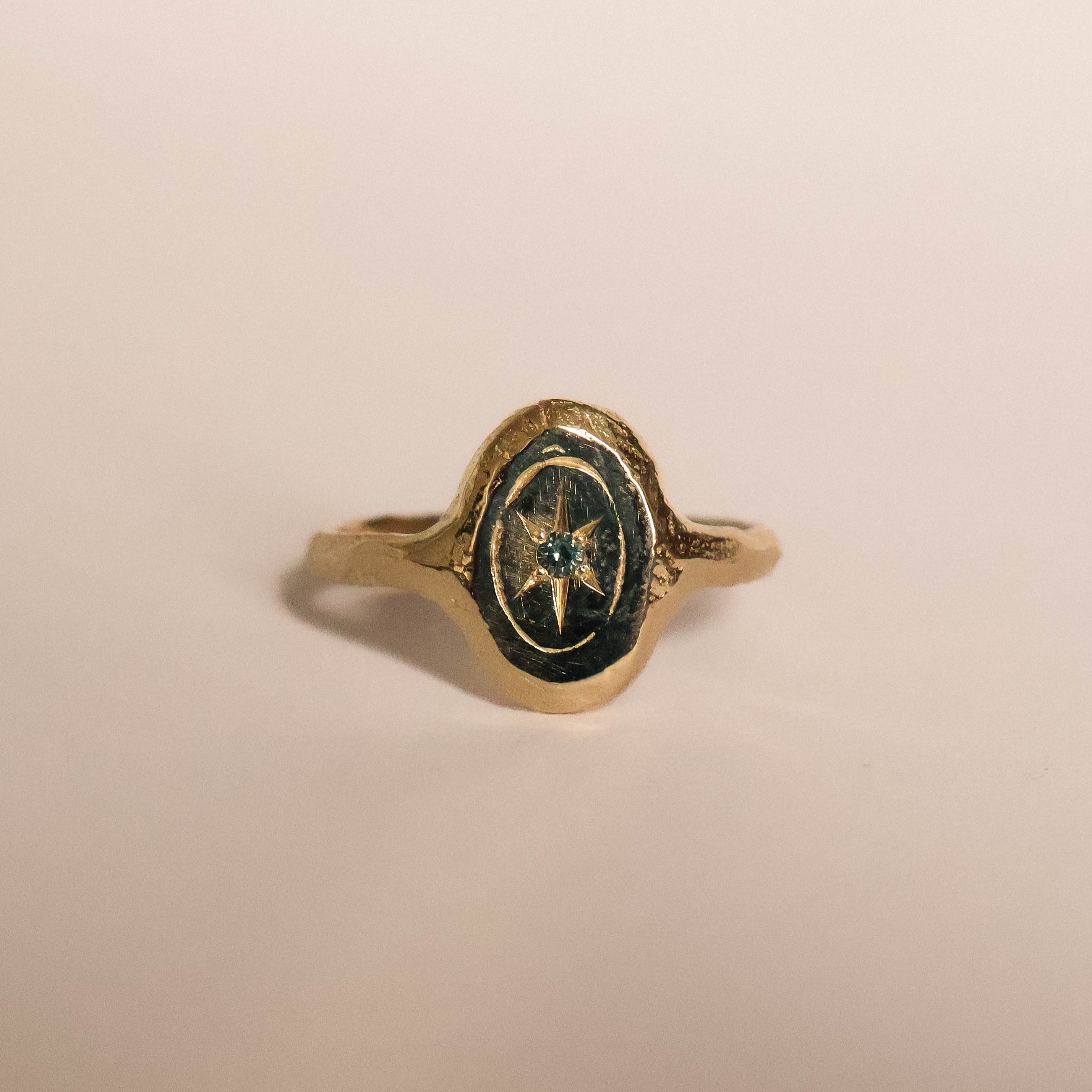 Gold ring with a star set blue sapphire on a beige background