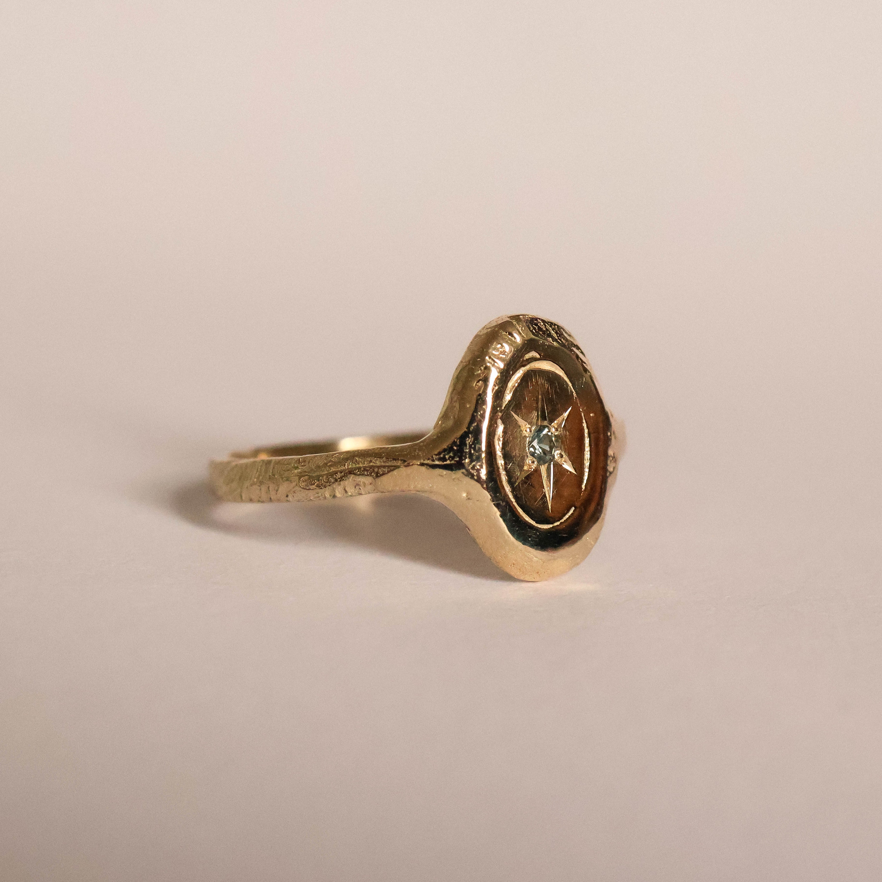 Gold ring with a star design on a beige background