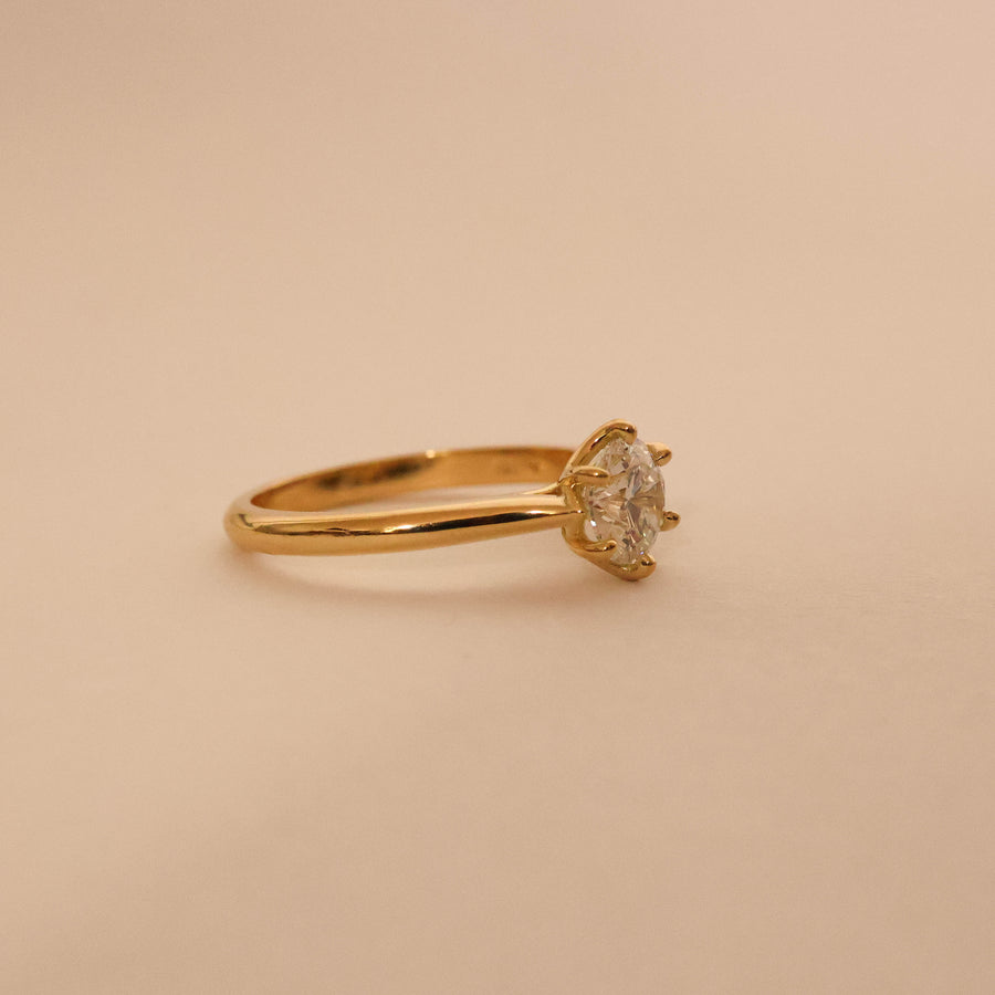 Gold ring with a diamond on a beige background