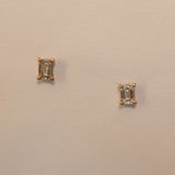 A pair of emerald cut diamond stud earrings in 9ct yellow gold, displayed against a light background.