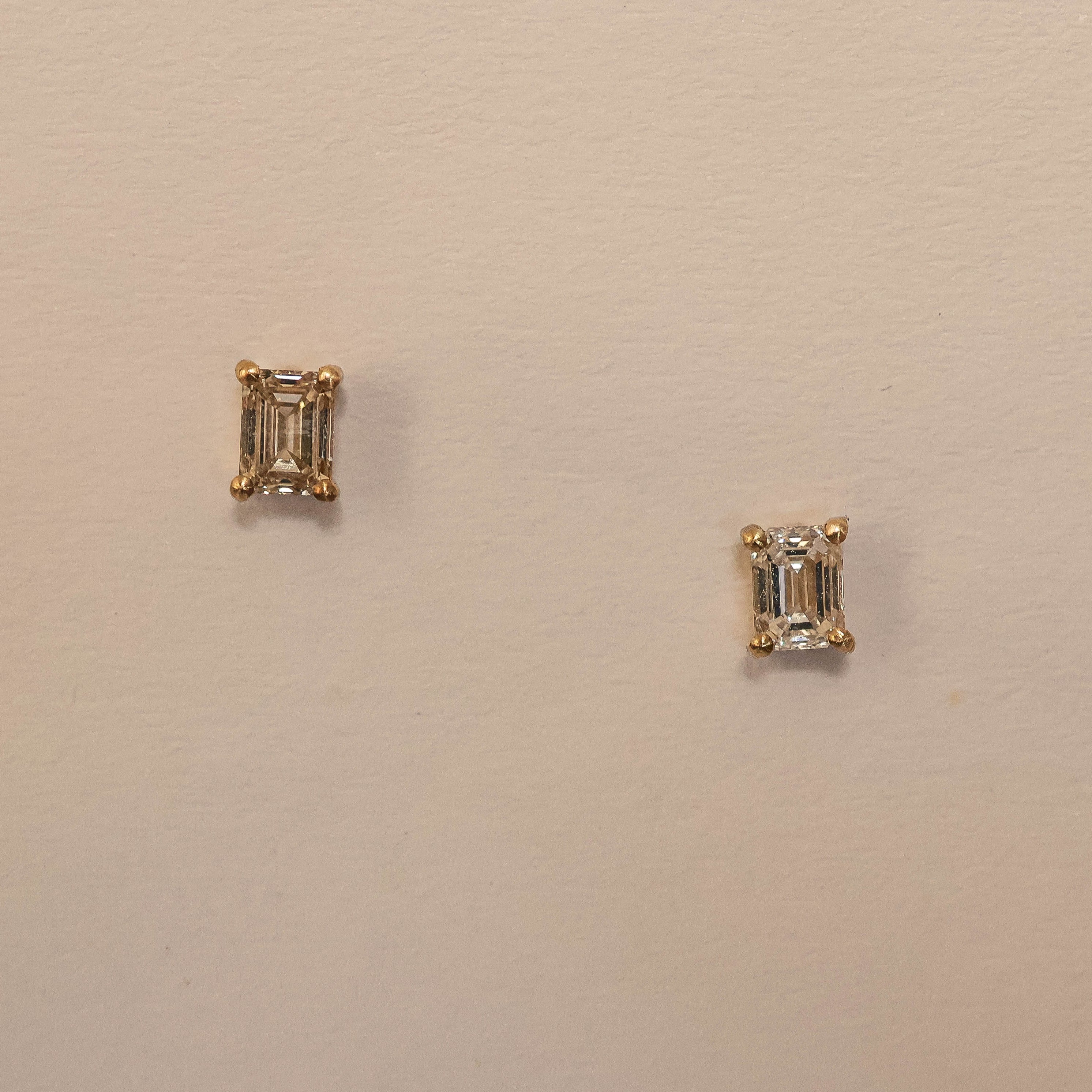 A pair of emerald cut diamond stud earrings in 9ct yellow gold, displayed against a light background.